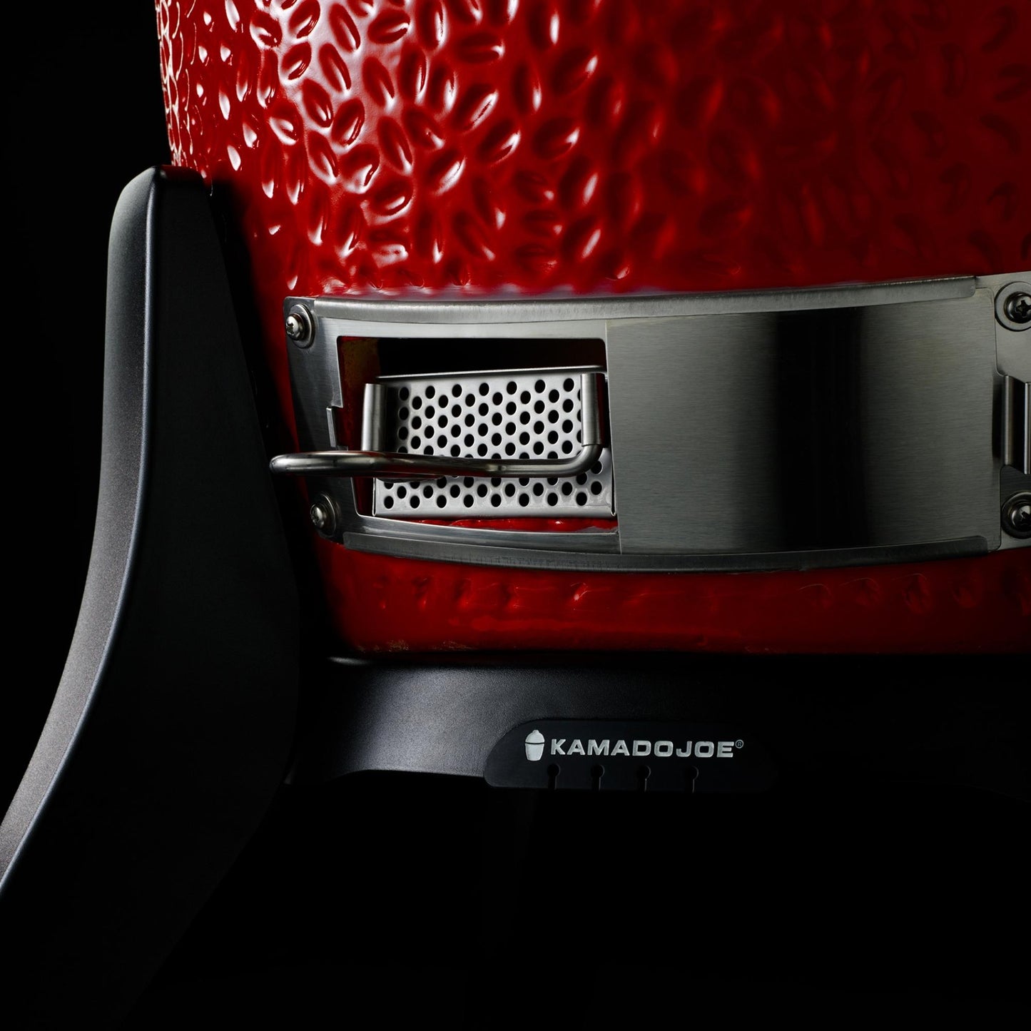 Close-up of a red Kamado Joe grill with visible branding on a black background