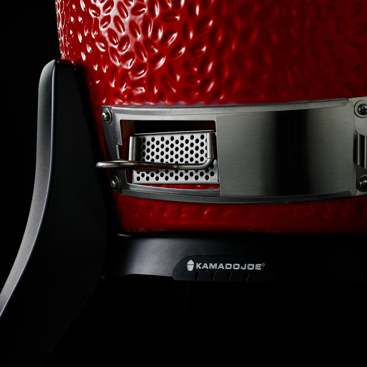Close-up of a red Kamado Joe grill with visible branding on a black background