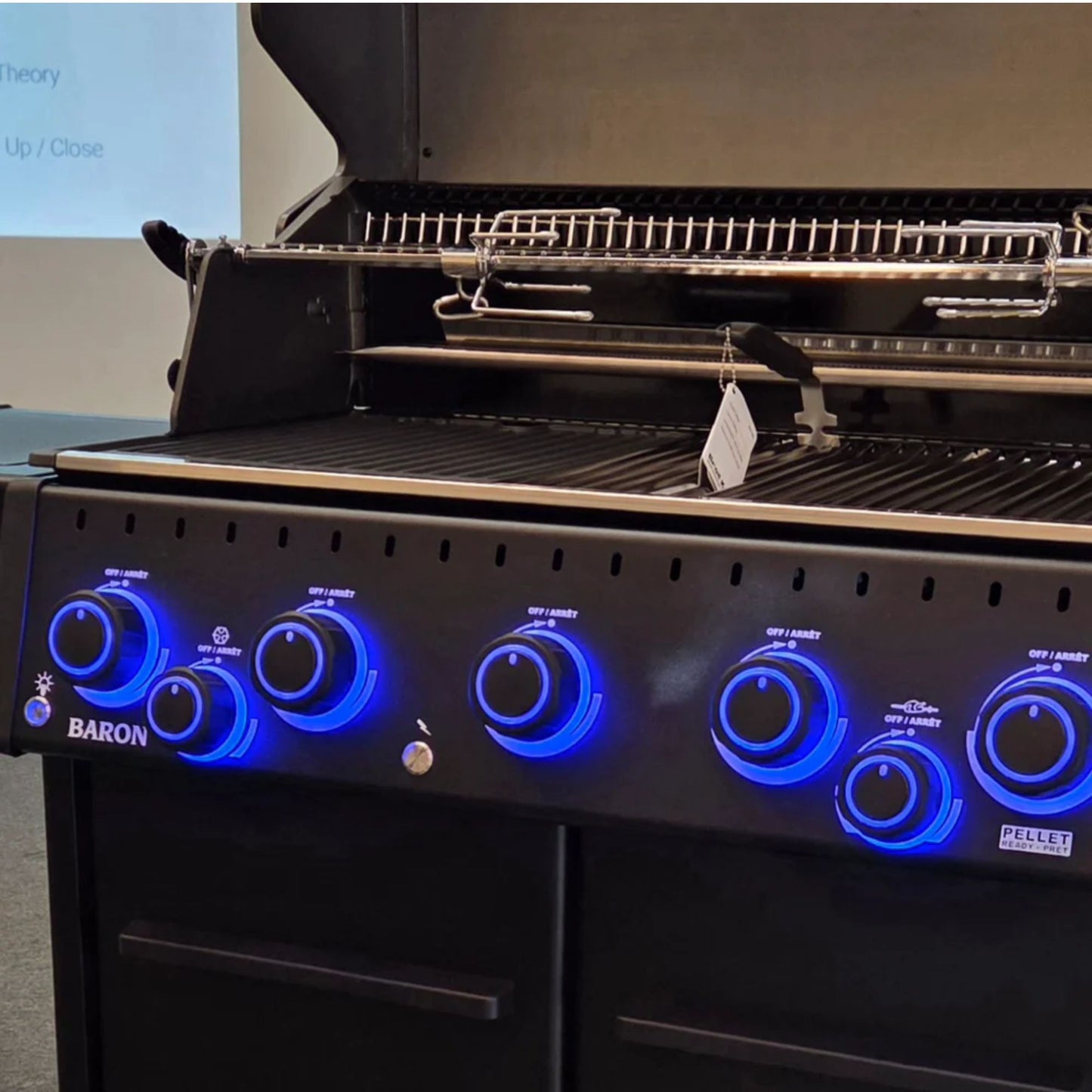 Close-up of illuminated control knobs and cooking area on the Broil King Baron 590 IRX Shadow Gas BBQ with rotisserie system.