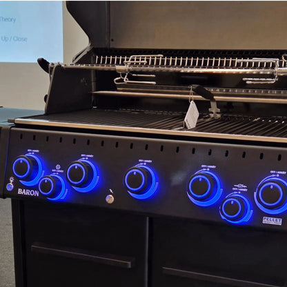 Close-up of illuminated control knobs and cooking area on the Broil King Baron 590 IRX Shadow Gas BBQ with rotisserie system.