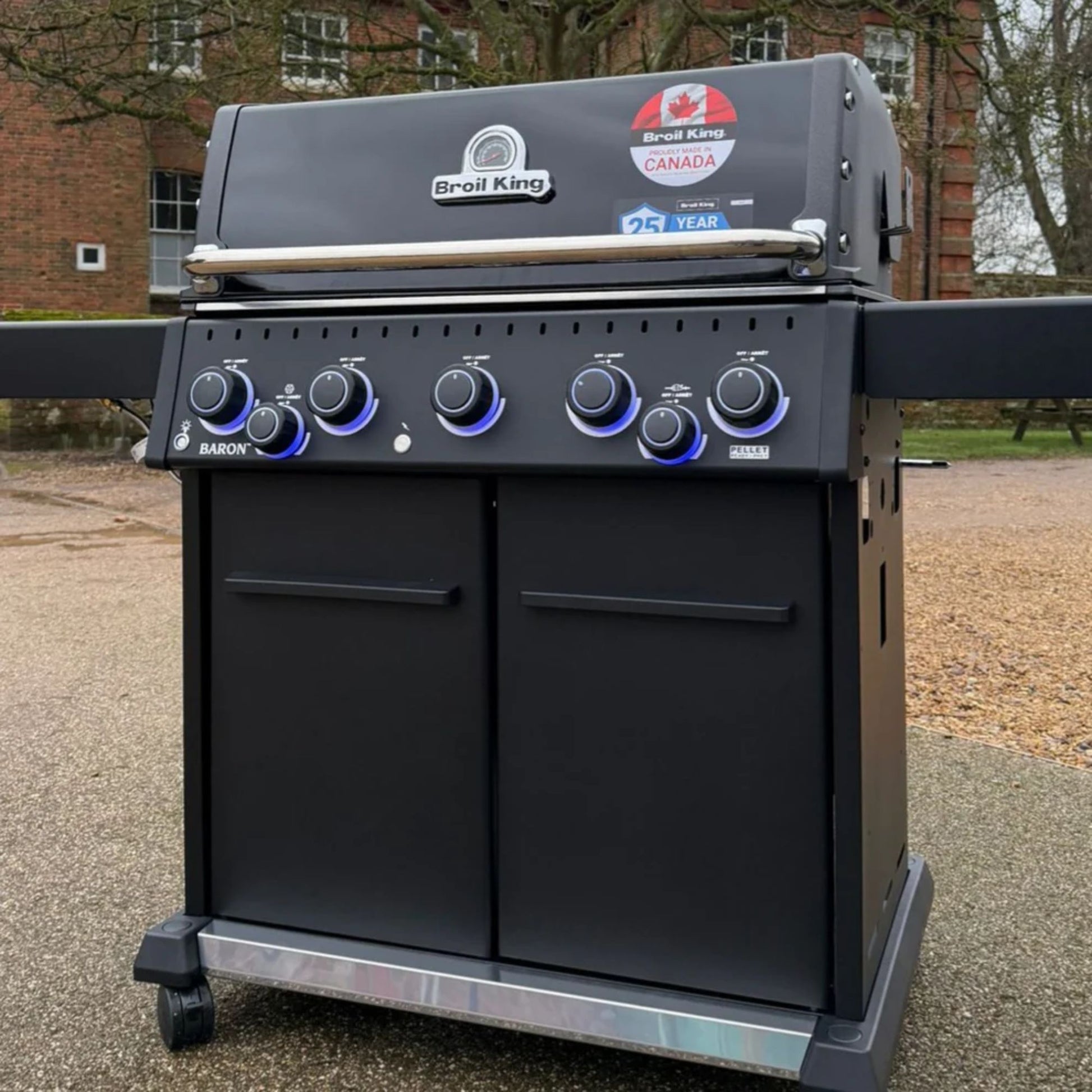 Broil King Baron 590 IRX Shadow Gas BBQ with enclosed cabinet base and illuminated control knobs outdoors.