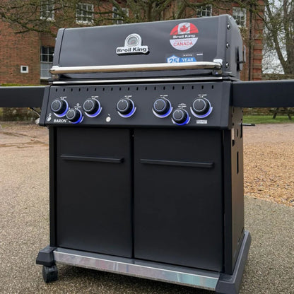 Broil King Baron 590 IRX Shadow Gas BBQ with enclosed cabinet base and illuminated control knobs outdoors.