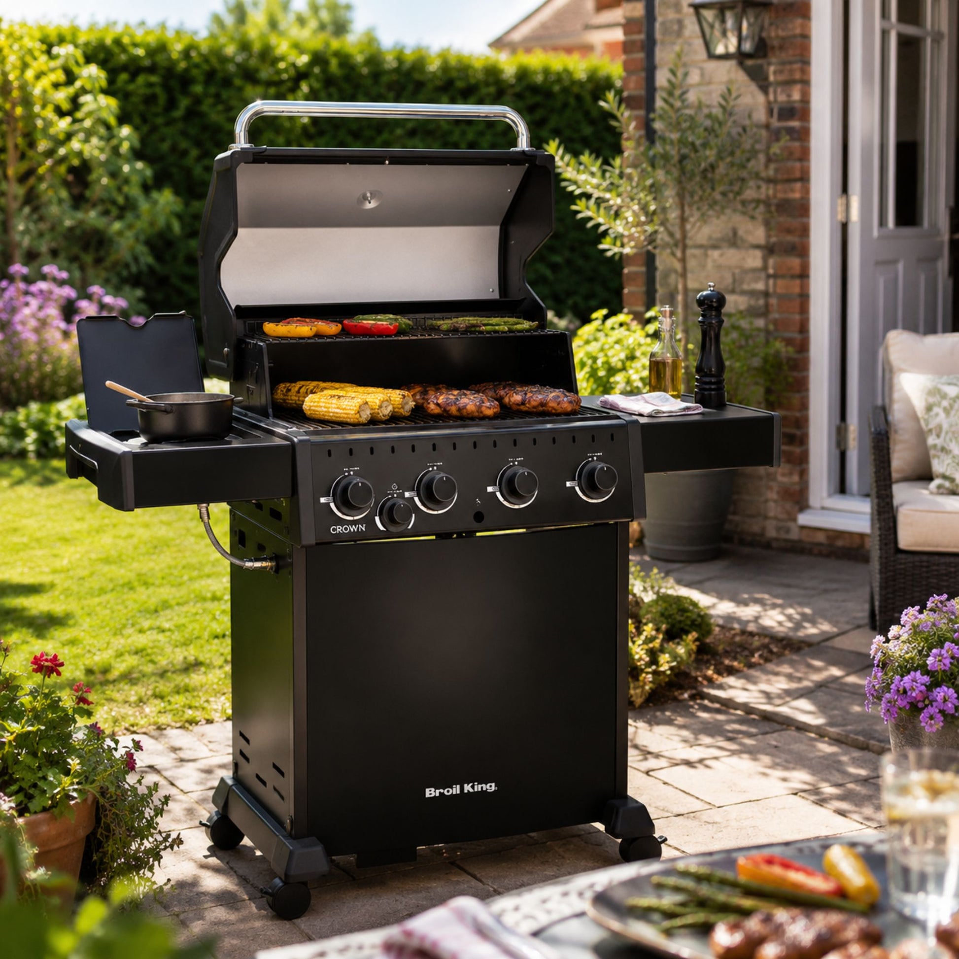 A Broil King gas BBQ cooking food on a patio area within the garden. 