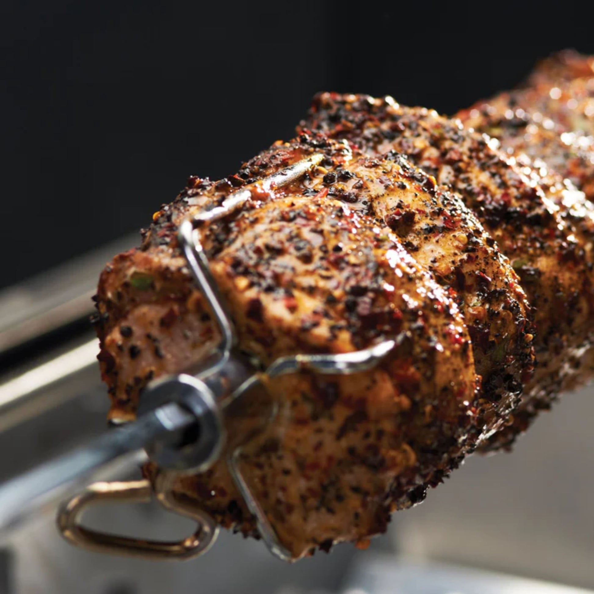 Grilled meat skewer on a metal skewer against a dark background