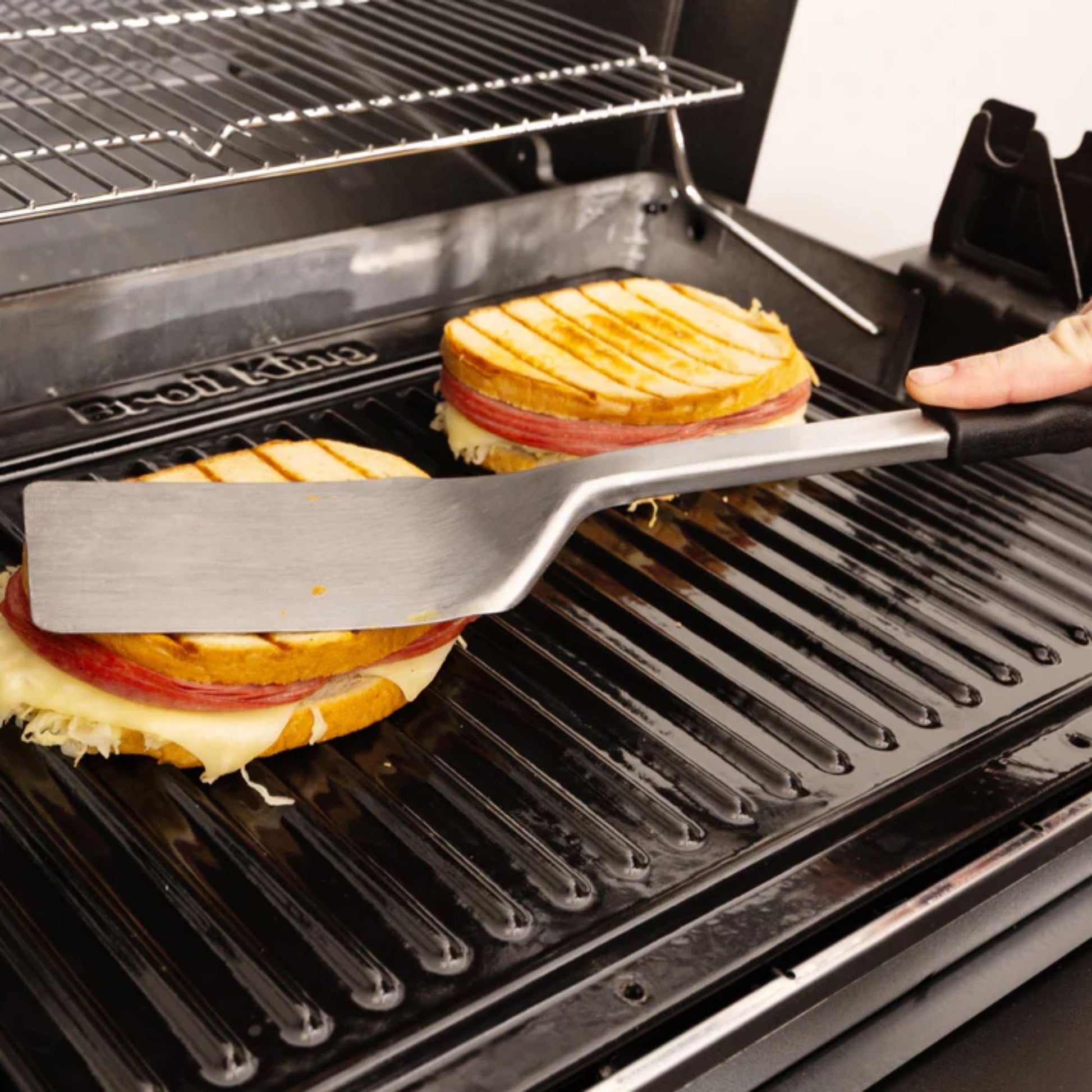 Grilled cheese sandwiches being prepared on a grill with tongs.