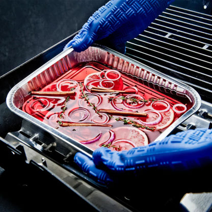 Person wearing blue gloves handling a tray of marinated meat and onions on a grill.
