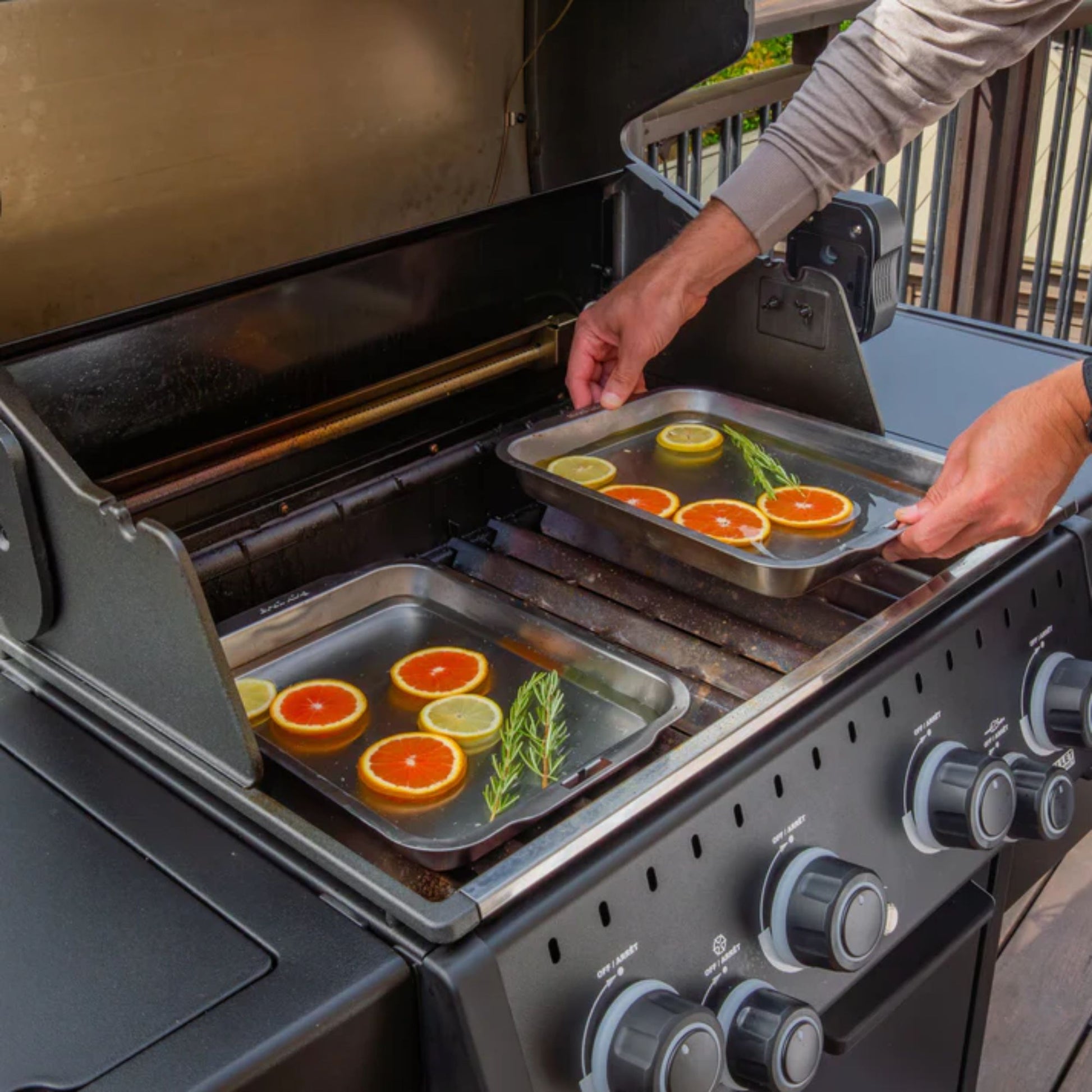Person preparing food on a portable grill with trays of vegetables.