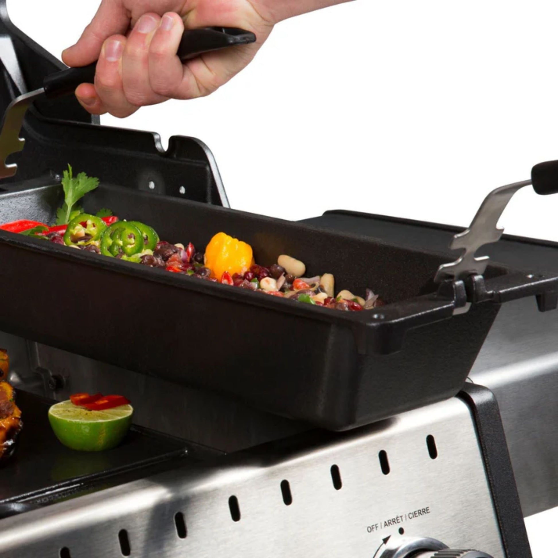 Person grilling vegetables on a portable grill pan with a white background