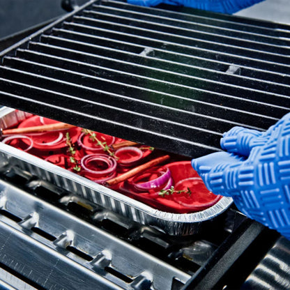 Person wearing blue gloves placing a tray of vegetables on a grill