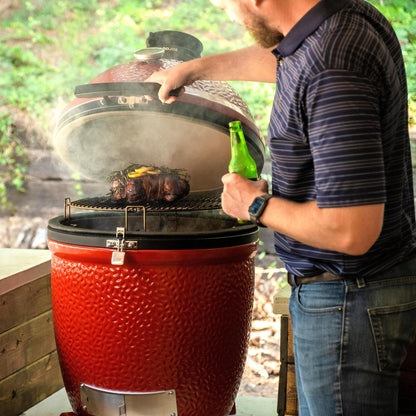 Man grilling outdoors with a red kamado-style grill