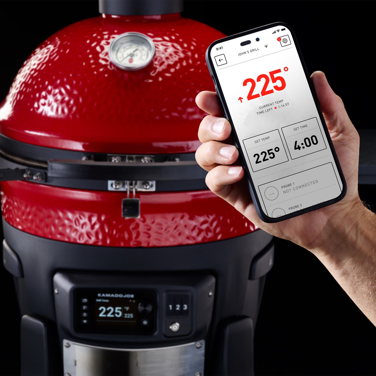Red Kamado Joe grill with a hand holding a smartphone displaying a cooking app.