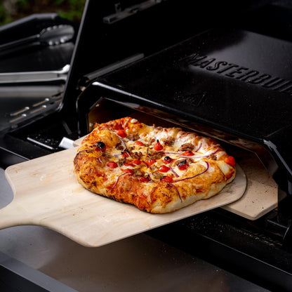 Pizza being taken out of a portable grill oven with 'Masterbuilt' branding.
