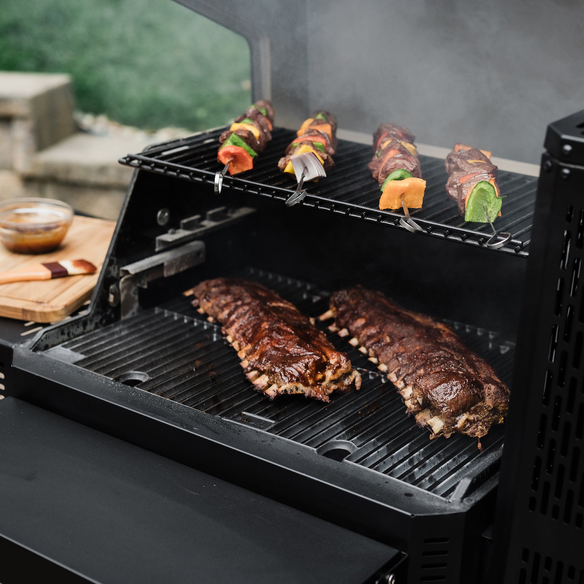 Barbecue grill with ribs and skewered vegetables cooking outdoors