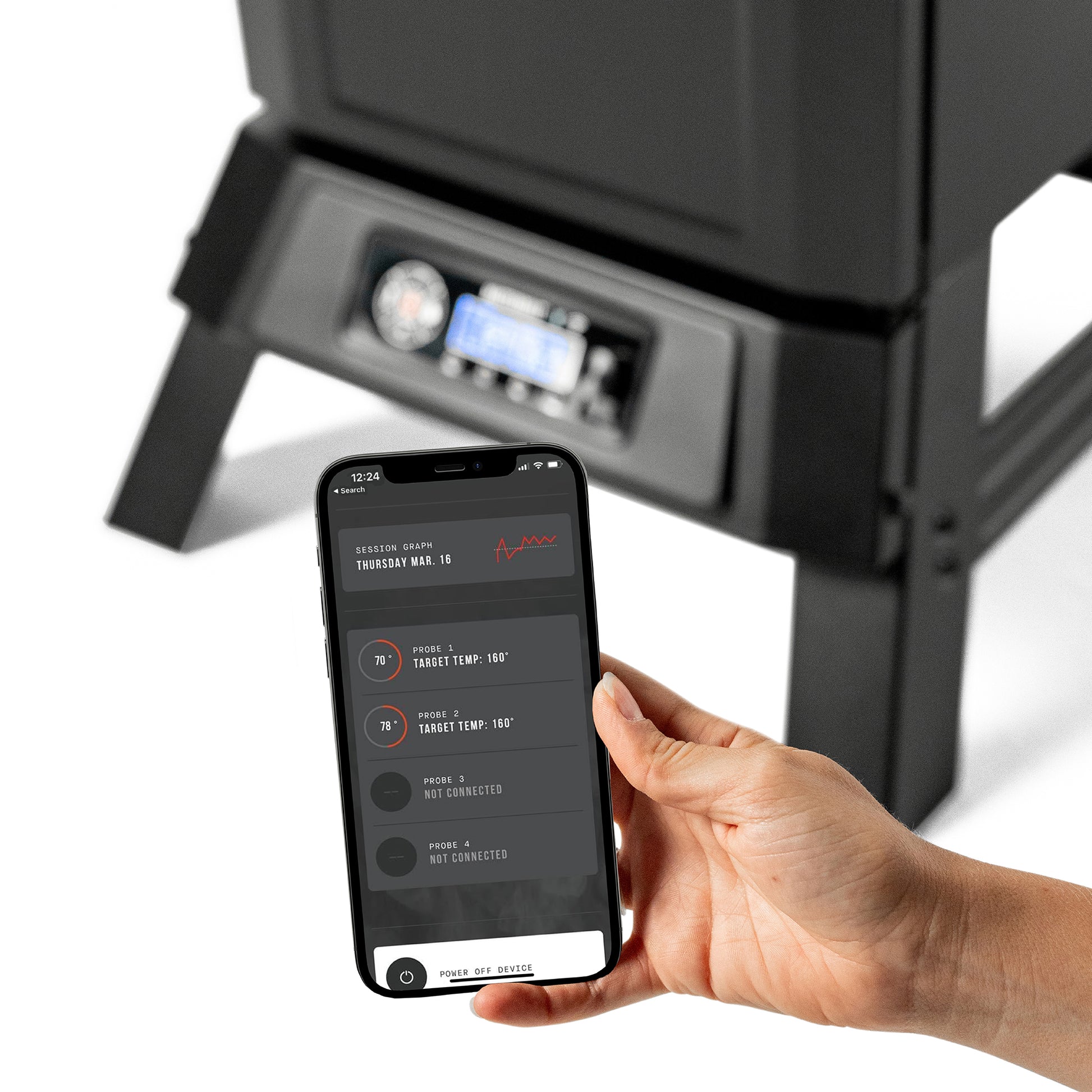 Hand holding a smartphone with Masterbuilt app interface in front of a 710 smoker.