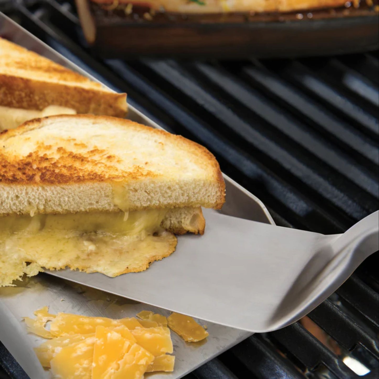 Grilled cheese sandwich being lifted from a grill with a spatula