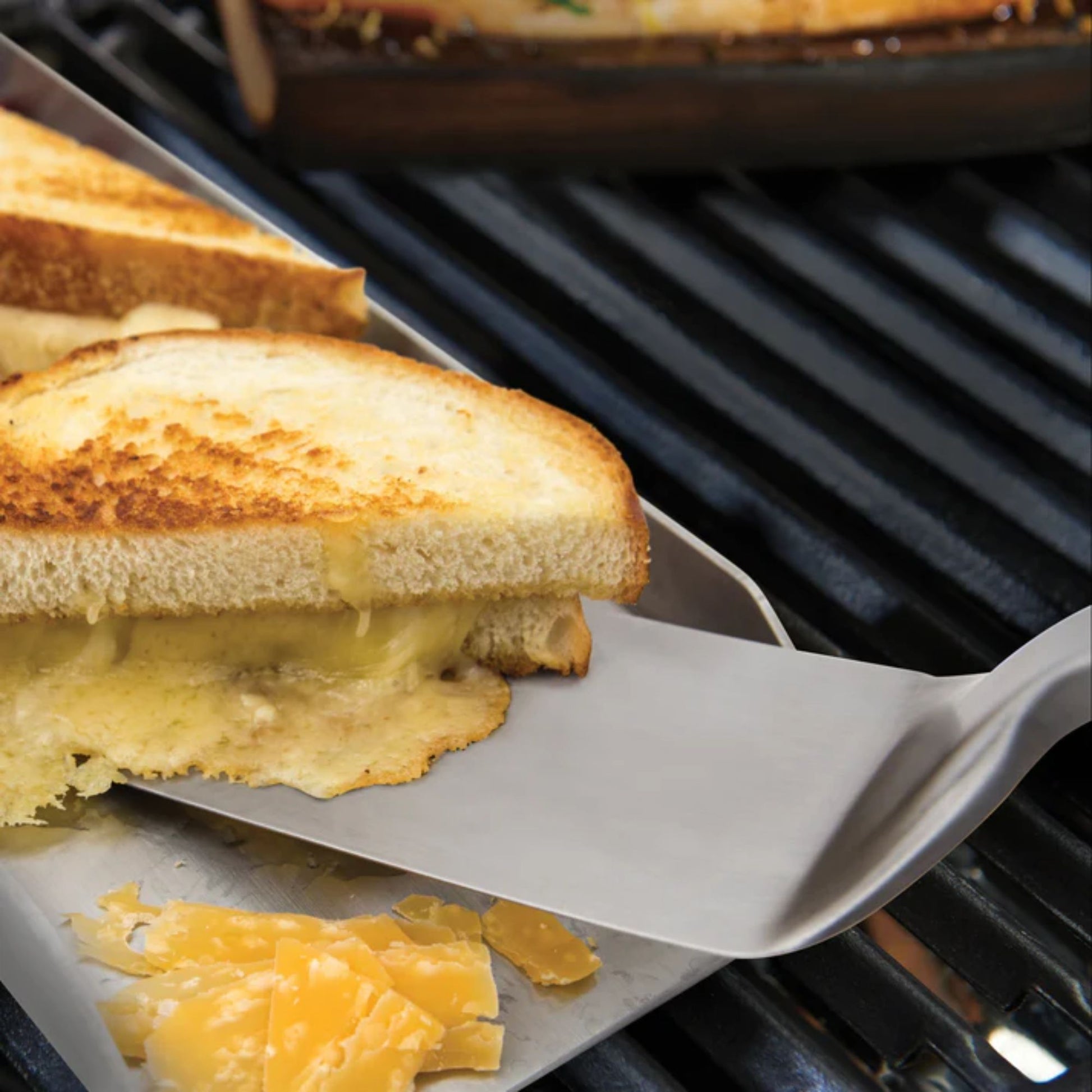 Grilled cheese sandwich being lifted from a grill with a spatula