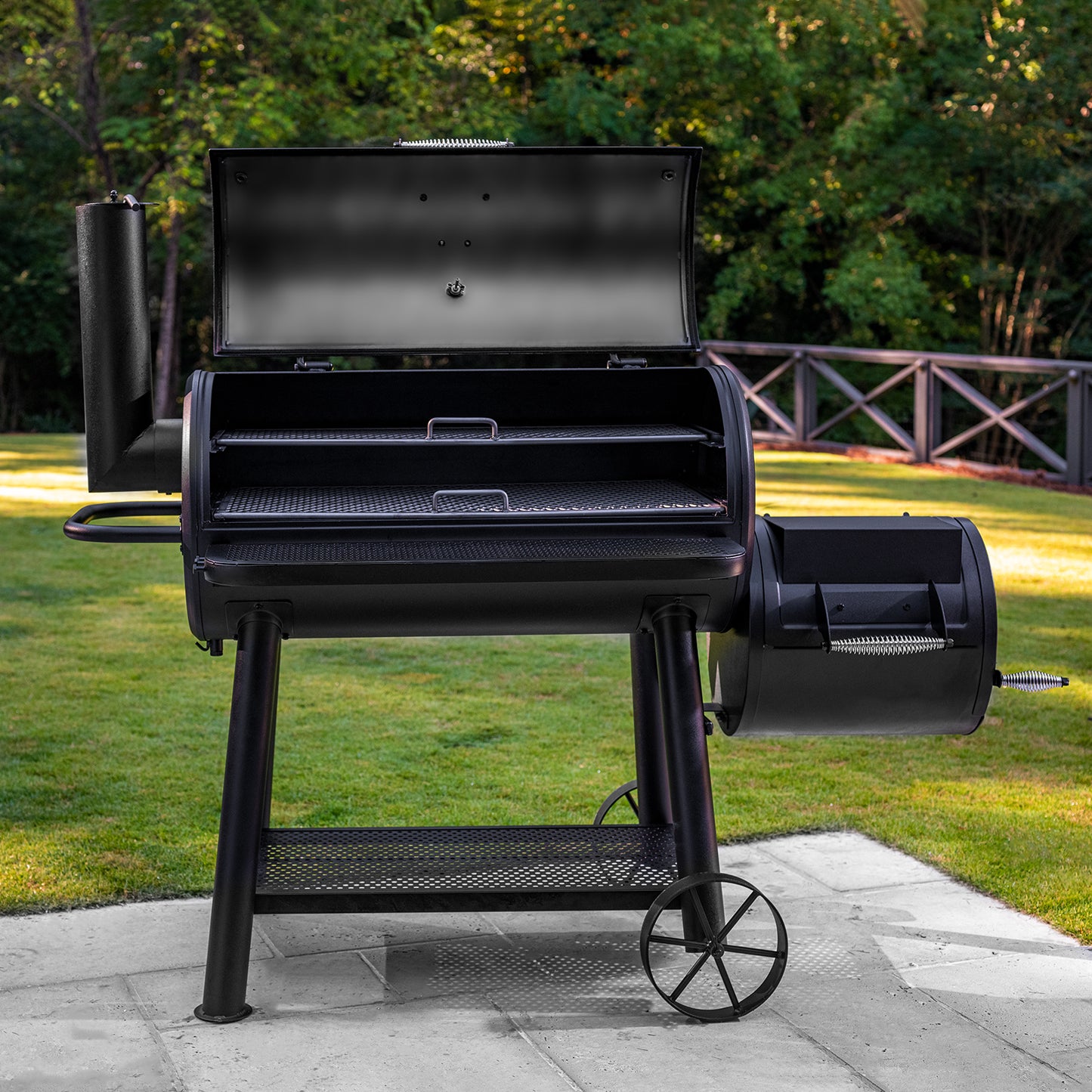 Black barbecue grill on a patio with greenery in the background