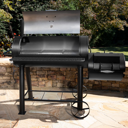 Black barbecue grill on a patio with stone wall and greenery in the background