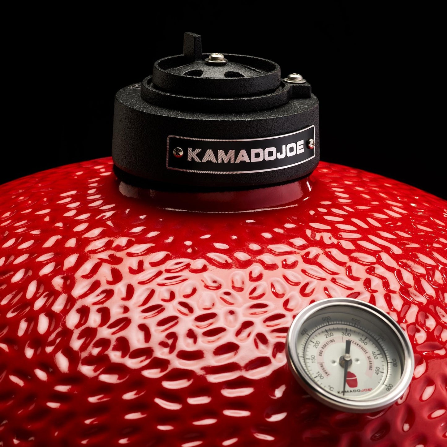 Red barbecue grill with 'Kamado Joe' branding and a thermometer on a black background