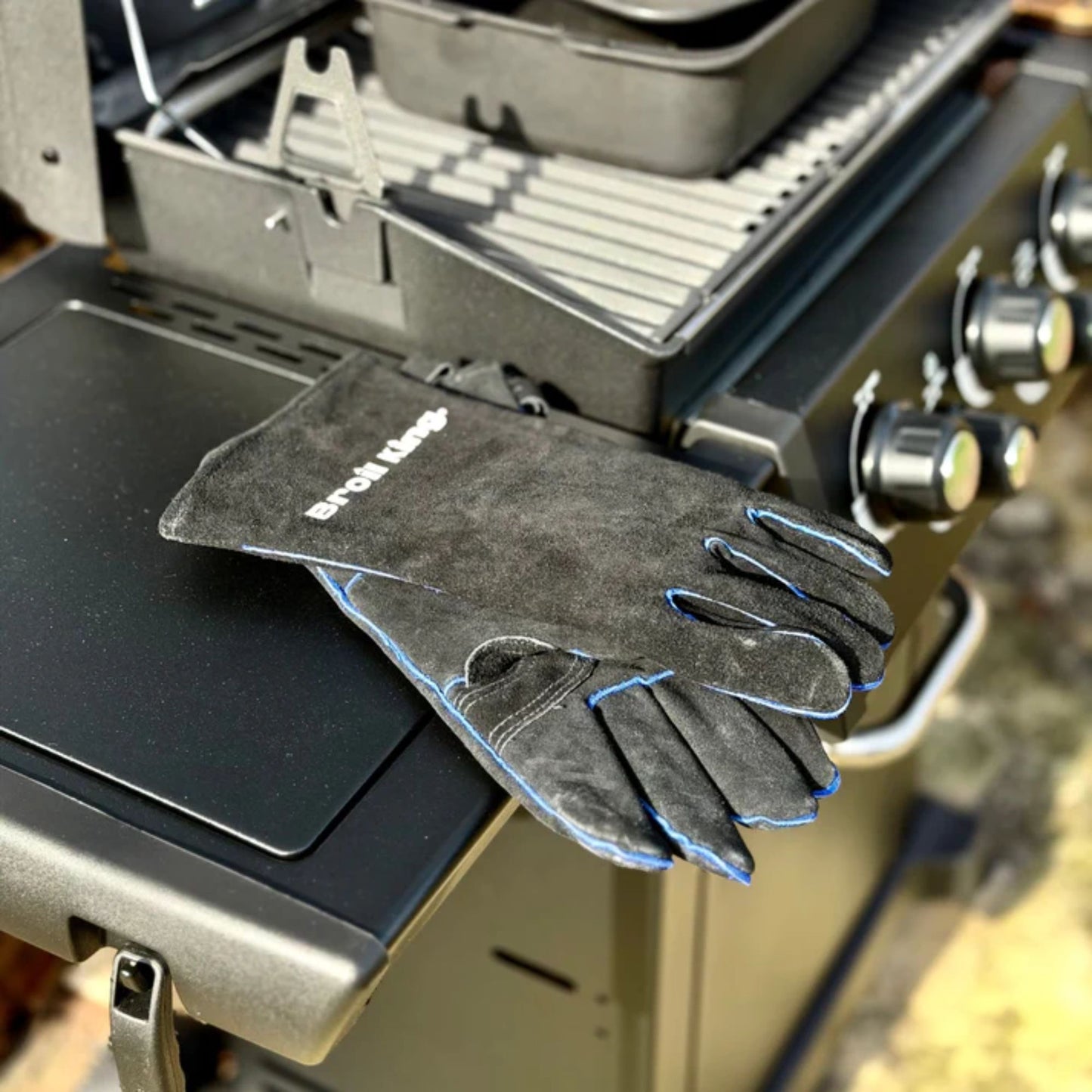 Black leather gloves sat on the side table of a BBQ. 