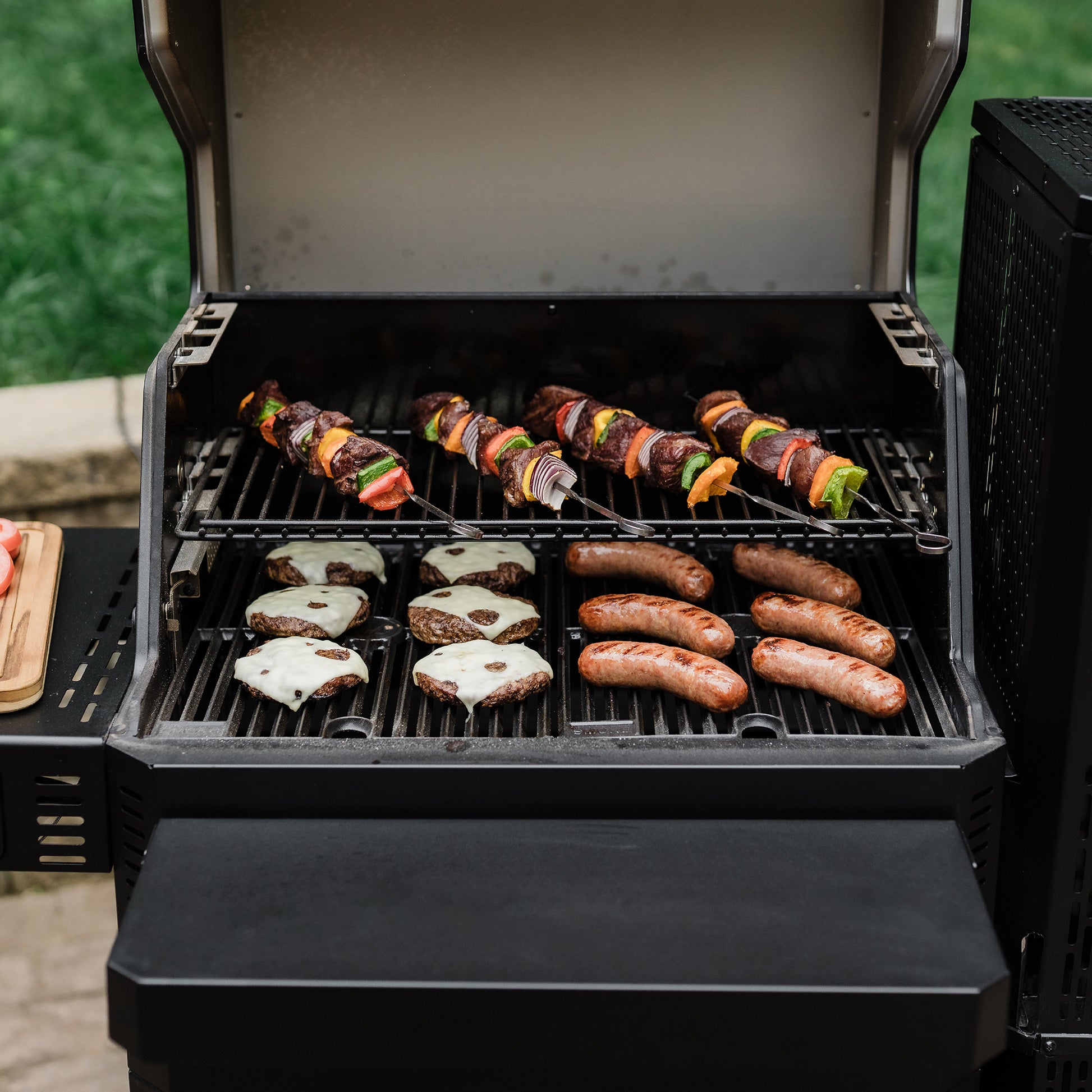 Grill with skewers and sausages being cooked outdoors