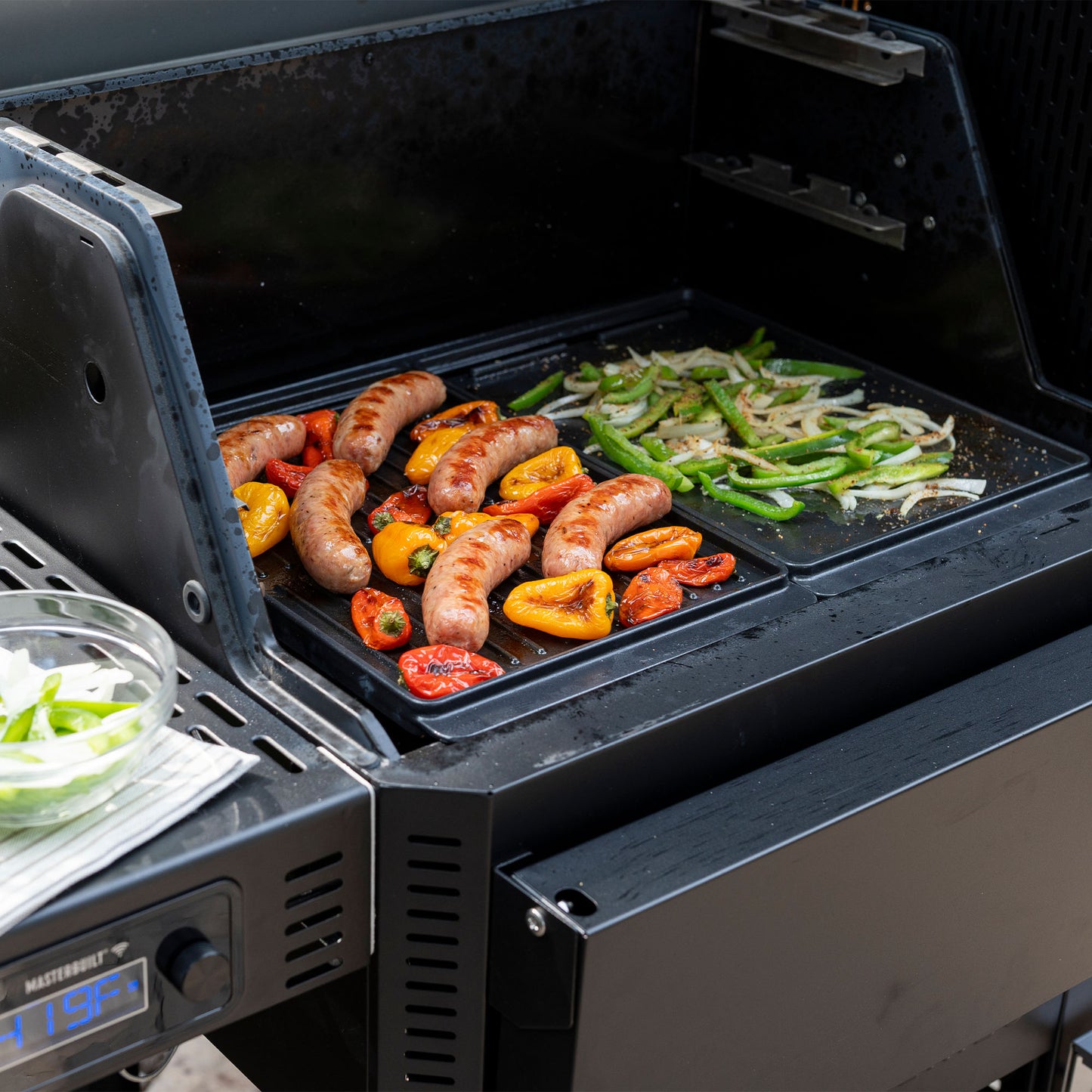 Grill with sausages and vegetables cooking on a portable grill